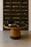 Wooden table with card games and a black suitcase in front of a wine rack.