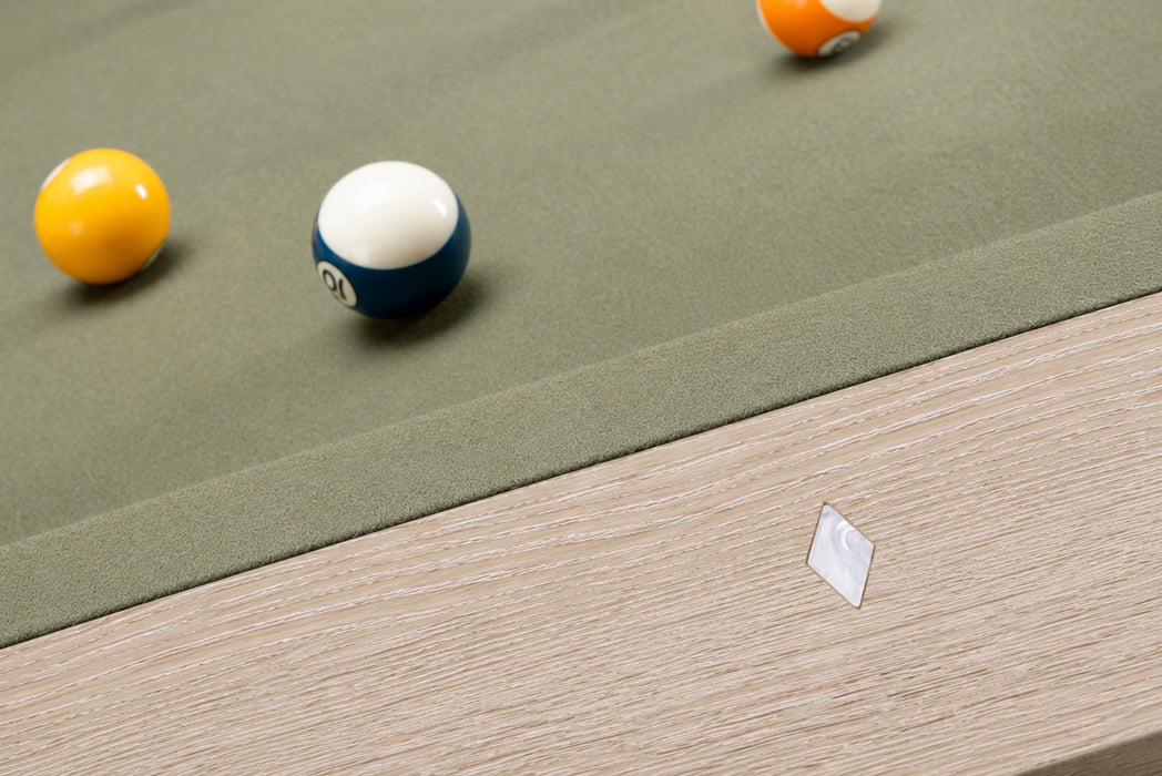 Close-up of a billiards table corner with a green felt surface, wooden side rail, and several pool balls including a yellow ball, a blue-and-white numbered ball, and part of an orange ball.
