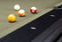 Four pool balls on a green felt billiards table with a black wooden rail in the foreground.