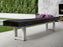 A covered bench sits near an American Heritage Lanai 12' Outdoor Shuffleboard Table in Pearl White.