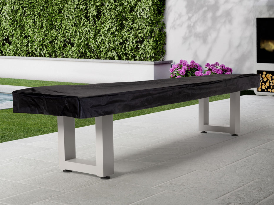 American Heritage Lanai 9' Outdoor Shuffleboard Table in Pearl White on a patio by greenery.