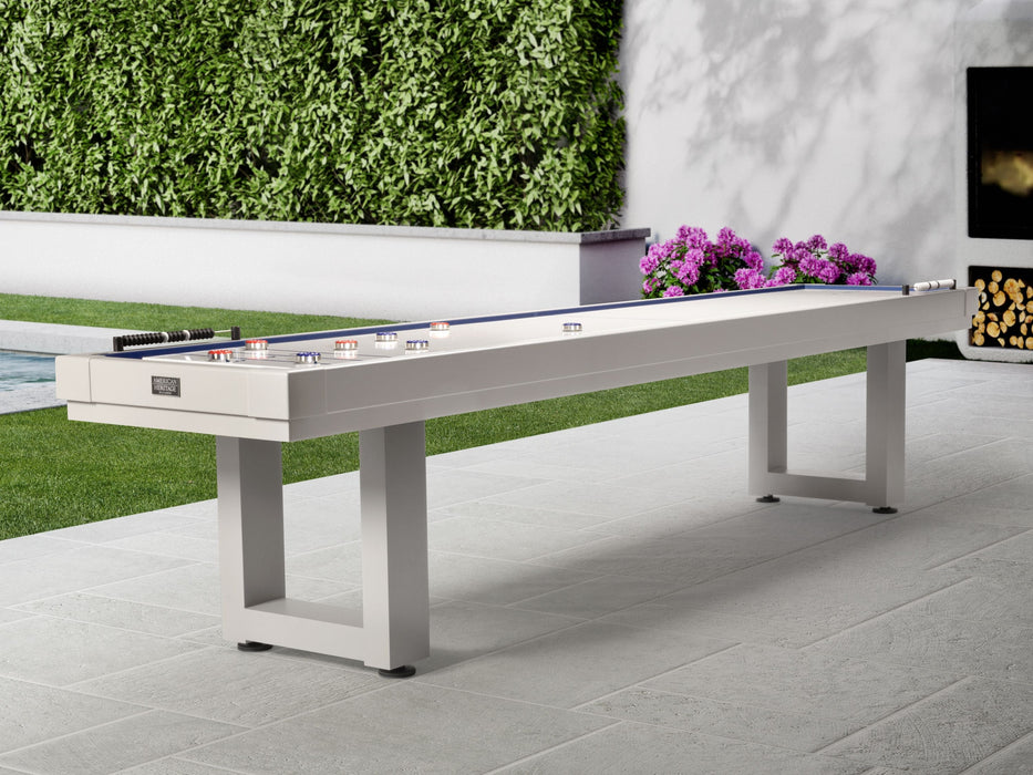 The American Heritage Lanai 9' Outdoor Shuffleboard Table in Pearl White sits amid patio greenery.