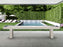 American Heritage Lanai 9' Shuffleboard Table in Oyster Grey, poolside on a landscaped patio.