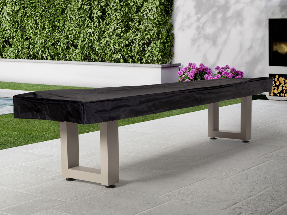 American Heritage Lanai 9' Outdoor Shuffleboard Table in Oyster Grey on patio near greenery.