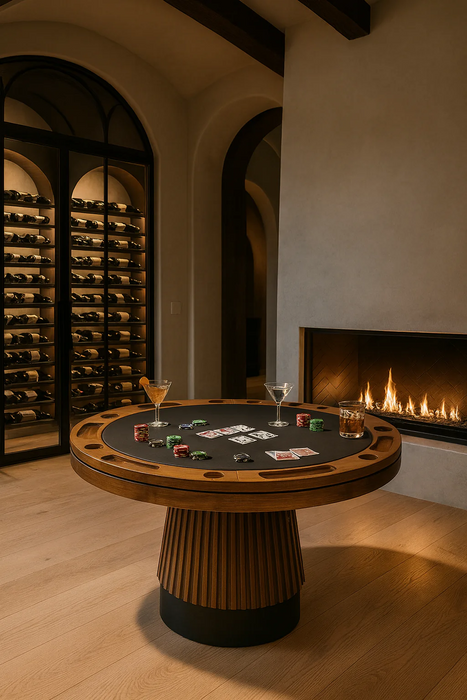 Round wooden table with playing cards and drinks in a room with wine bottles and a fireplace.
