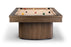 A modern pool table with a thick rectangular wood frame and a cylindrical ribbed wood base, shown on a clean white background with several billiard balls on the tan felt surface.