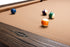 Close-up of a BenNSWIK pool table with a tan felt surface and dark wood frame, showing several billiard balls on the table.