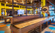 Game room with Champion 20' Competition Elite Shuffleboard Table, pool tables, yellow walls, modern decor.